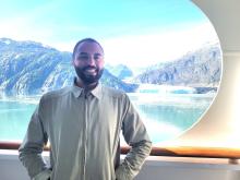 A photo of Dr. Hannibal Person smiling in front of a view of mountains and water. 